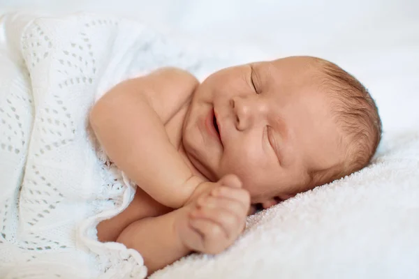 笑って 白い毛布で寝て ベッドの上に横たわる小さな新生児男の子を笑顔 — ストック写真