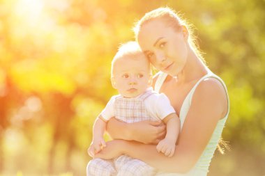 Şirin Bebek anne çim ile parkta. tatlı bebek ve anne açık havada. Annem bir yürüyüş ile duygusal çocuk gülümsüyor. bir çocuğun bir gülümseme