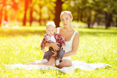 Şirin Bebek anne çim ile parkta. tatlı bebek ve anne açık havada. Annem bir yürüyüş ile duygusal çocuk gülümsüyor. bir çocuğun bir gülümseme