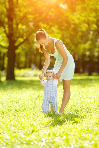 夏は草の上の母親と一緒に公園でかわいい赤ちゃん 甘い赤ちゃんとママの屋外 徒歩でママと感情的な子供の笑みを浮かべてください 子供の笑顔 — ストック写真