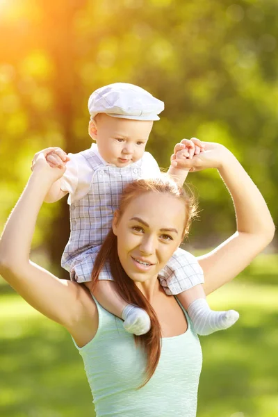 草の上の母親と一緒に公園でかわいい赤ちゃん 甘い赤ちゃんとママの屋外 徒歩でママと感情的な子供の笑みを浮かべてください 子供の笑顔 — ストック写真