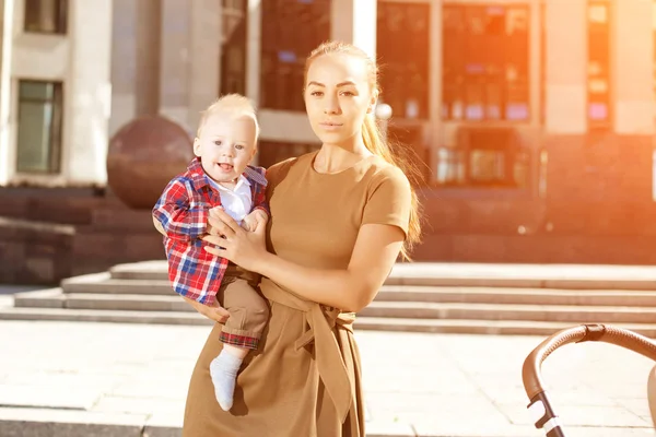 乳母車と街のトレンディな近代的な母 若い母親は 都会の子と歩きます 赤ちゃん車で子供と美しい若い女性 — ストック写真
