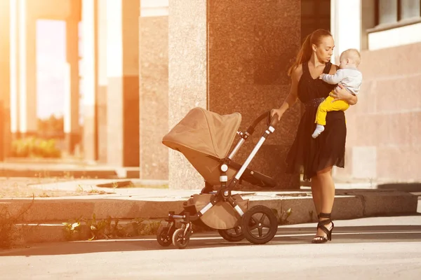 乳母車と街のトレンディな近代的な母 若い母の子供と歩く — ストック写真