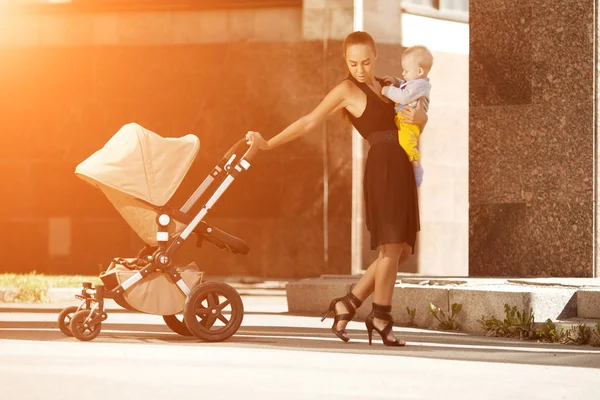 乳母車と街のトレンディな近代的な母 若い母の子供と歩く — ストック写真