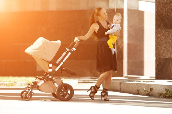 乳母車と街のトレンディな近代的な母 若い母の子供と歩く — ストック写真