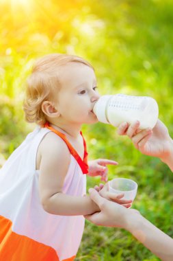 Çocuk bir şişeden bebek maması yiyor. Toddler bebek yemek yeme. Annem çocuk yayınları.