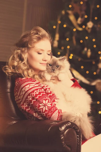 Christmas party, winter holidays woman with cat. New year girl. christmas tree in interior background.