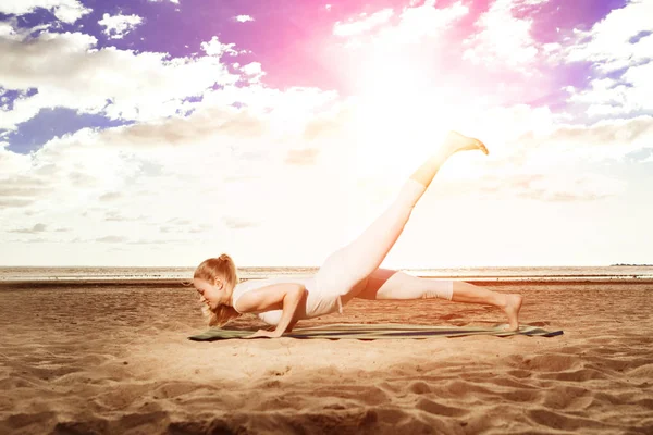 年轻漂亮苗条的女人在日落时分在海滩上瑜伽 瑜伽在日出 — 图库照片
