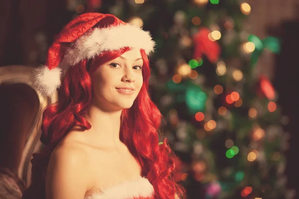 年轻美丽微笑着圣诞老人的女人靠近圣诞树 时尚奢侈品女孩庆祝新的一年 免版税图库图片