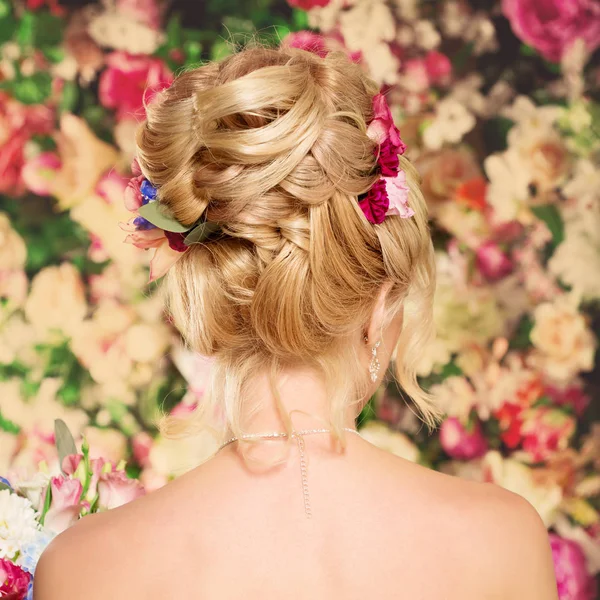 結婚式のヘアスタイルは若い女の子 彼女の髪に花を持つ女性 高い積み重ね カールの束 美しい金髪のモデル イヤリングと花束 — ストック写真