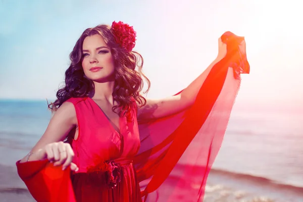 海沿いの明るい赤いドレスを着た美しい少女 Lanshaft の背景 日差しの中 日没でロマンチックな女性 — ストック写真