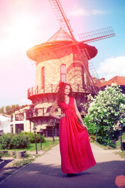 ミルの背景に明るい赤のドレスで美しい女性 — ストック写真