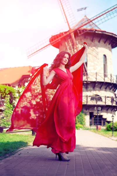 ミルの背景に明るい赤のドレスで美しい女性 — ストック写真