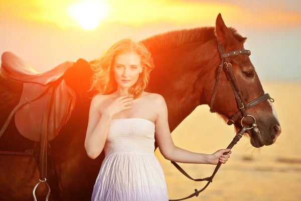 美しい女性のビーチで夕暮れ時の乗馬します 海で太陽の光線で馬との若い美しさの少女 — ストック写真