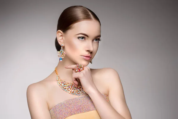 Beautiful woman in a necklace, earrings and ring. Model in jewelry from precious stones, diamonds.