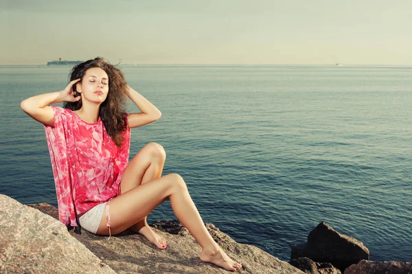 水の背景と岩のビーチのファッションの女の子 海のそばの長い足と日焼けのスリムな美人モデル 旅行や休暇について夏シーン — ストック写真