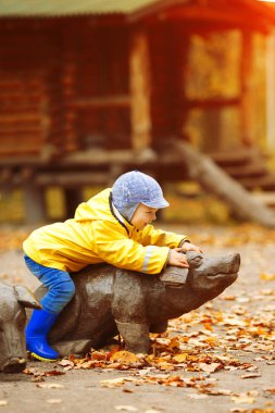 Sonbahar parkının arka planındaki küçük çocuk. Akçaağaç yaprağı olan çocuk. Sonbahar sahnesi.