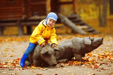 Sonbahar parkının arka planındaki küçük çocuk. Akçaağaç yaprağı olan çocuk. Sonbahar sahnesi.