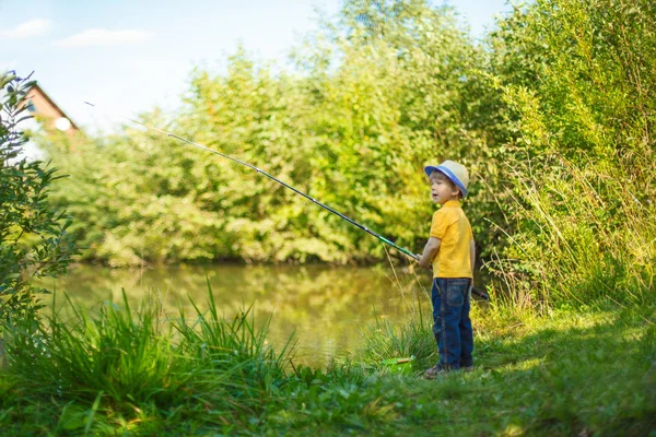 Little boy is engaged in fishing in a pond. Child with a dairy in his hands.