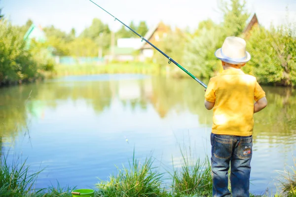 Little boy is engaged in fishing in a pond. Child with a dairy in his hands.