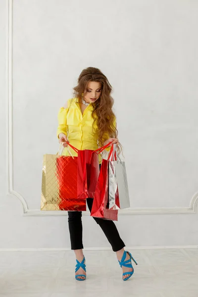 Shopping girl. Woman with bags. A model with new heels in a fashionable blouse with open shoulders. Concept of megamalls and sales.