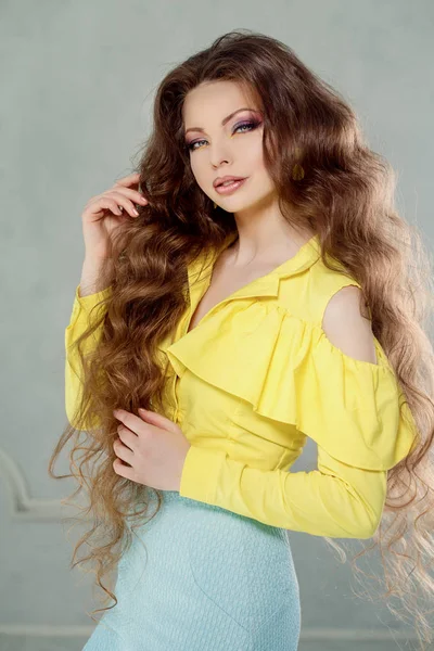 一个美丽的现代女孩的肖像 长卷发在黄色的衬衫没有肩膀 时尚的女装 — 图库照片