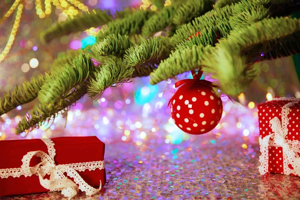 Christmas card. Background on a theme of New Year\'s  party. Decorated fir-tree with gifts and candles on the background of colorful festive lights. A magical evening.