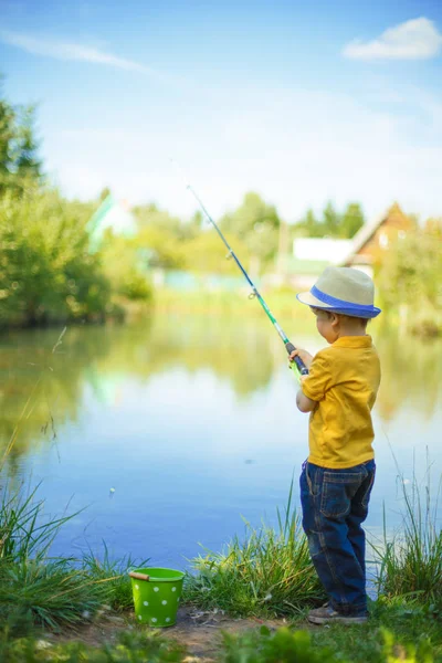 少年は池で釣りをしている 乳製品を手にした子供は ストック写真