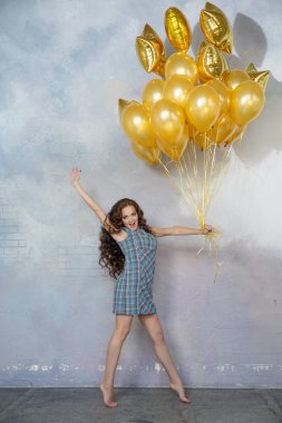 Altın bir balon tutan genç ince kadın.
