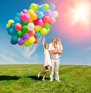 mutlu bir aile renkli balonlar açık tutuyor. Anne, ded ve iki kızı oynamaya