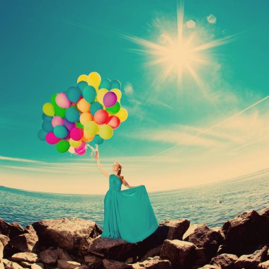 balon gökyüzüne karşı sahilde elinde ve güneşin uzun elbiseli kadın lüks moda şık