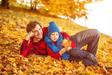 Baba ile oğlu sonbahar parkta yürüyor. Bir çocuk ve bir adam ormanda yürüyüşe eğleniyorlar. Aile doğada zaman harcıyor
