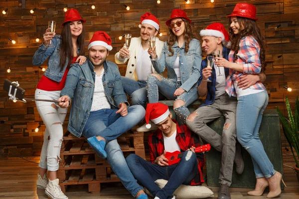 サンタさんの帽子を身に着けているグループの友達とのパーティー 良いと肯定的な気分を共有流行に敏感な若い人たちは 特別な機会を祝うため 新しい年の大晦日のパーティーやクリスマス深夜 — ストック写真