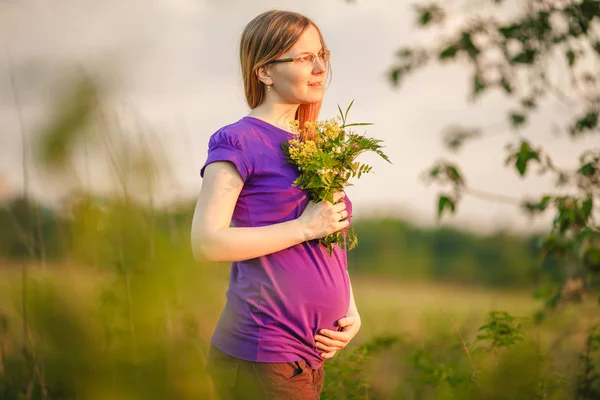 夕日と自然の背景に妊娠中の女性 バックライトで 太陽の下でおなかを持つ美しい少女モデル — ストック写真