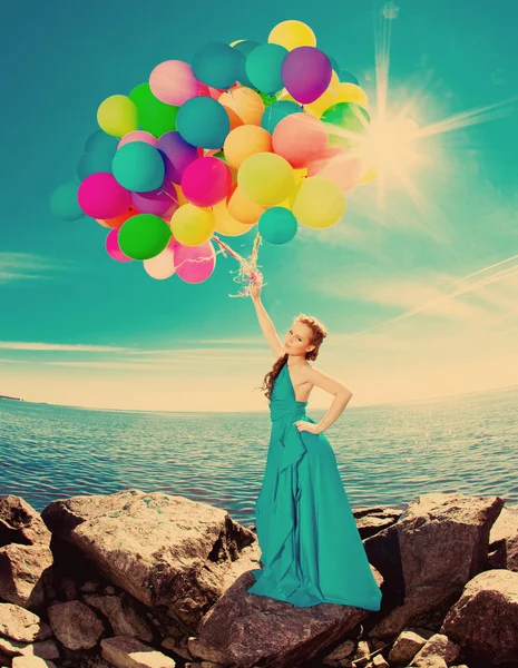 高級ファッション スタイリッシュなと女性と空に対して浜辺で手で風船ロングドレスの太陽 — ストック写真