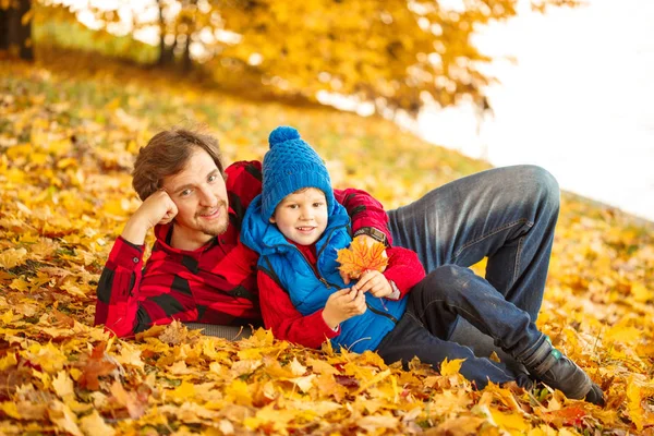 Baba ile oğlu sonbahar parkta yürüyor. Bir çocuk ve bir adam ormanda yürüyüşe eğleniyorlar. Aile doğada zaman harcıyor
