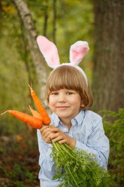 Bir ormandaki bir havuç ile bir takım elbise bunny bebek çocuk. Çocuk tavşan kulakları ile.