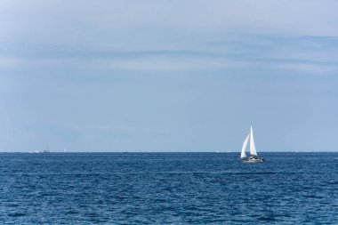 Yelkenli parlak mavi okyanus ötesinden kayar