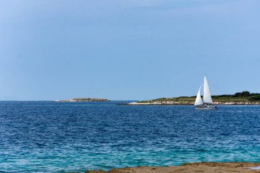 Yelkenli parlak mavi okyanus ötesinden kayar