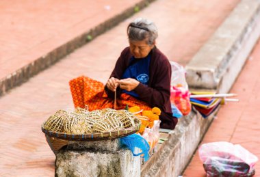 Luang Prabang, Laos - 11 Ocak 2017: Kadın bir şehir hasır sepetleri sokak satıyor. Metin için yer kopyalayın