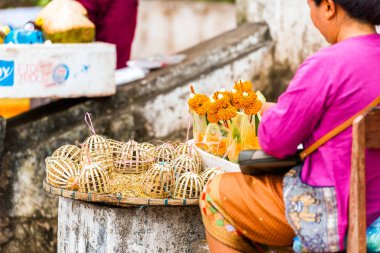 Woman sells sacrifices from the leaves of bananas and flowers, Luang Prabang, Laos. Close-up clipart