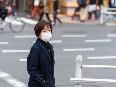 Tokyo, Japonya - 7 Kasım 2017: Bir şehir sokak üzerinde beyaz bir tıbbi maske bir kadın. Metin için yer kopyalayın