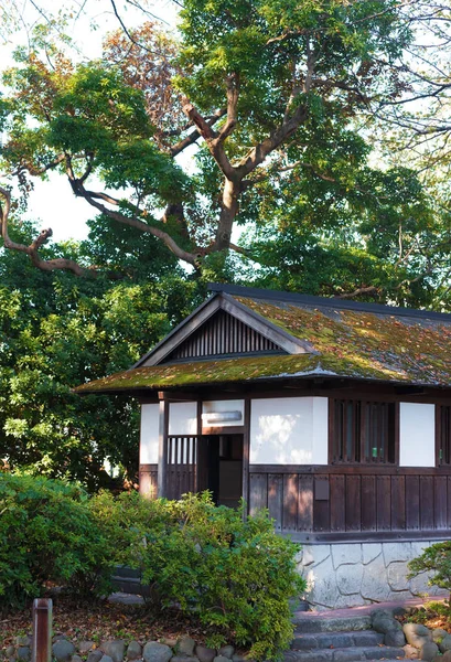 A wooden building with moss on the roof, among the trees, Odawara, Japan. Vertical