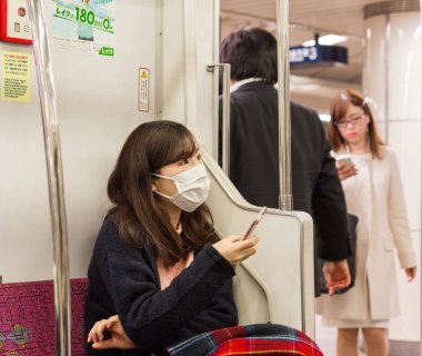 Tokyo, Japonya - 7 Kasım 2017: Bir kız tıbbi maskeli bir metro arabada oturur
