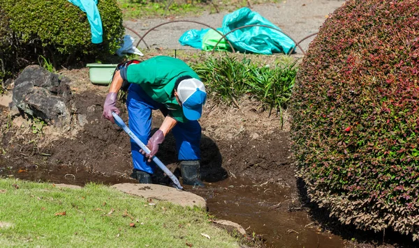 Hombre Con Una Pala Cava Barro Canal Con Agua Parque —  Fotos de Stock