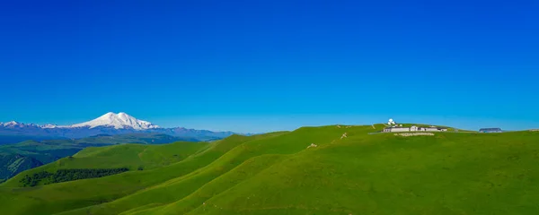 Green Meadow Hills fondo Elbrus en un día de verano. Panorama — Foto de Stock