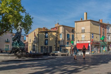 AGDE, FRANCE - 19 Temmuz 2020: Eski binalarla dolu Agde Merkezi ve çeşmede bir heykel, kasabanın sokak manzarası