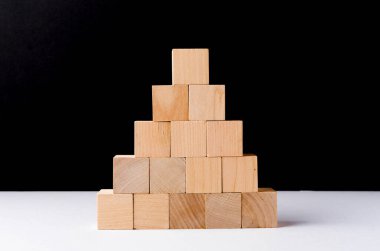 Siyah arka planda tahta küpleri istiflemek. İlerleme ya da bir şey inşa etme konsepti.