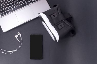 Akıllı telefonlu sanal gerçeklik gözlükleri, siyah arka planda laptop. Seçici odak.