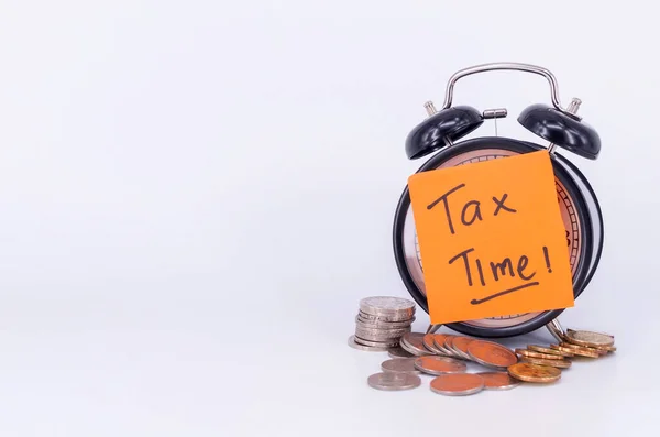 目覚まし時計とコインの白い背景に税金の時間 選択的焦点 — ストック写真